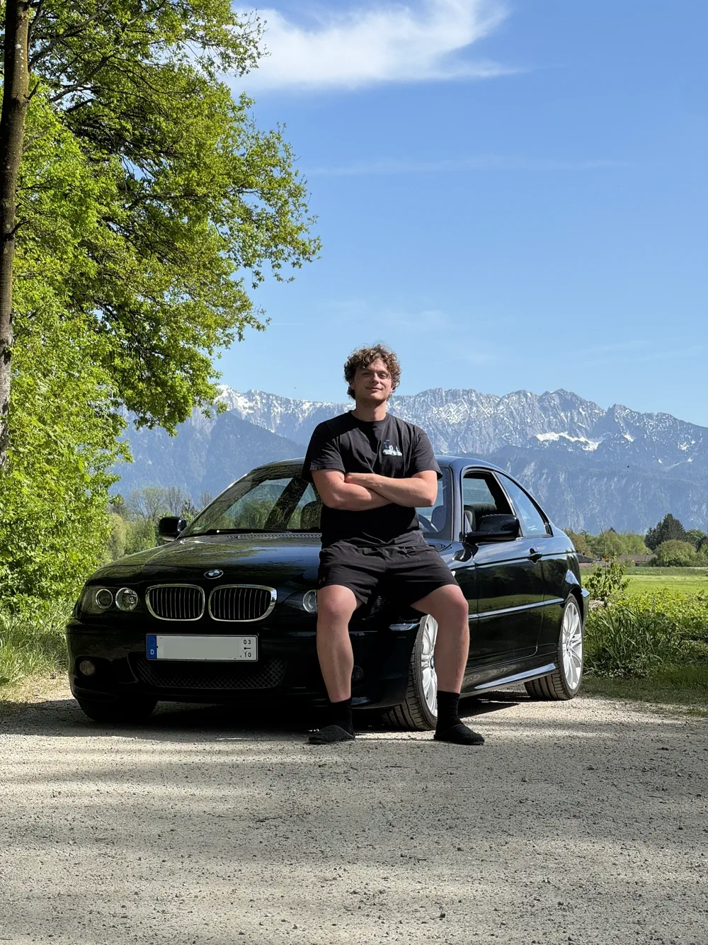 Maximilian Haak vor seinem BMW E46 mit Alpenpanorama